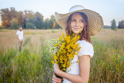 Portrait of smiling young woman standing on field