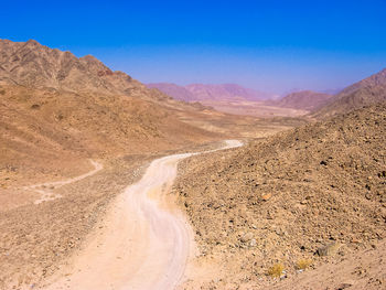 Scenic view of desert against clear blue sky