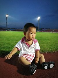 Portrait of boy sitting on grass at night