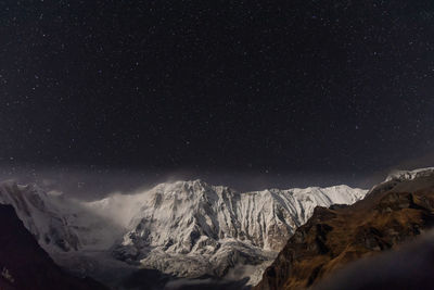 Scenic view of snowcapped mountains against sky at night