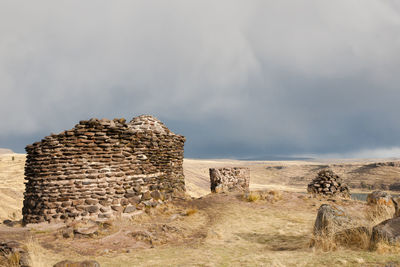 Stone wall on landscape against sky