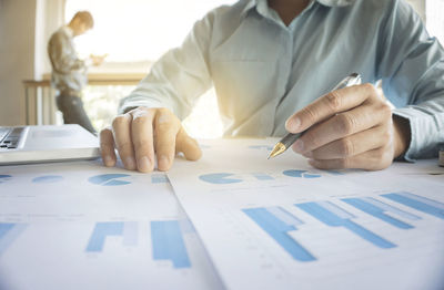 Midsection of businessman working over graph in office