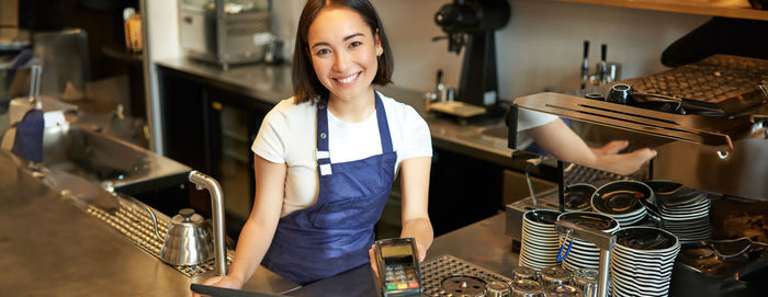 Portrait of young woman using mobile phone in cafe