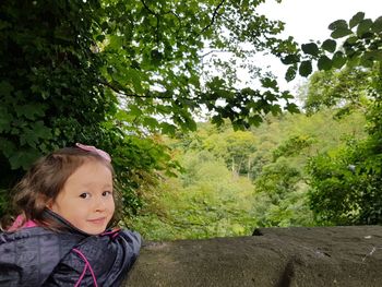 Portrait of cute girl amidst plants against trees