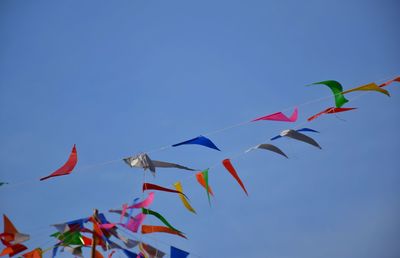 Low angle view of flags against clear blue sky