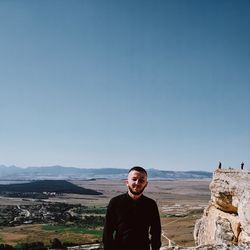 Portrait of man standing on mountain against clear sky