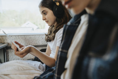 Girl wearing bluetooth headphones while watching tablet pc in train