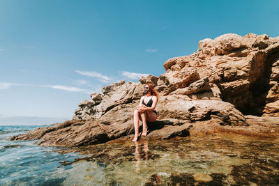 Woman standing on rock against sky