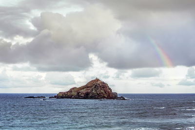 Scenic view of rainbow over sea against sky