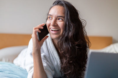 Young woman using mobile phone while sitting at home