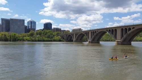 Bridge over river in city against sky