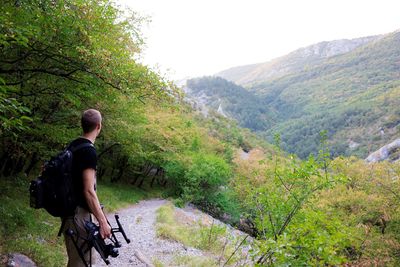 Rear view of man standing on mountain against clear sky