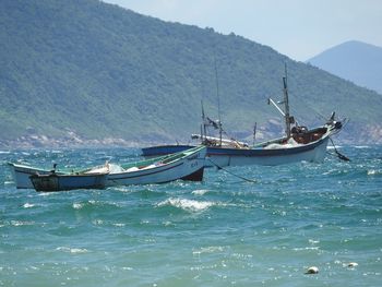 Boats moving in river against mountain