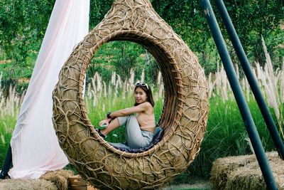 Portrait of woman sitting on tree trunk