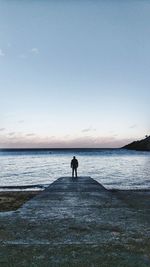 Silhouette man standing on beach against clear sky