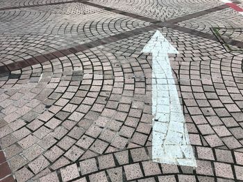 High angle view of arrow symbol on cobblestone street