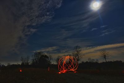 Firework display on field against sky at night