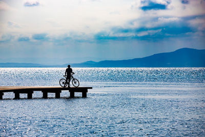 Man sitting on sea against sky