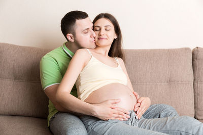 Portrait of couple kissing against wall