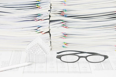Close-up of model house with eyeglasses and pencil on financial documents