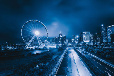 Illuminated ferris wheel in city