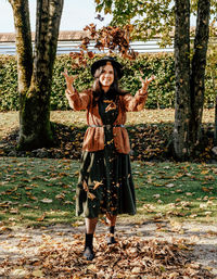 Front view of young woman throwing autumn leaves in air. fall colors, happy, positive emotion.