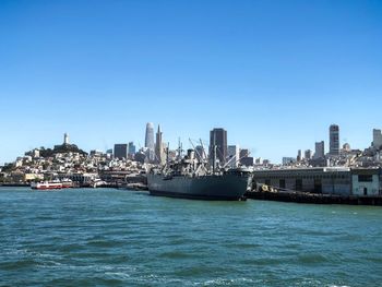 Sea by buildings against clear blue sky