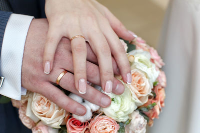 Midsection of bride and groom holding bouquet during wedding ceremony 