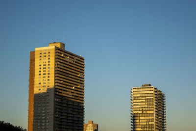 Low angle view of modern buildings against clear sky at sunset.