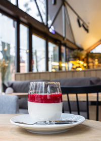 Delicious italian dessert panna cotta with red berry sauce on table, cafe interior background.