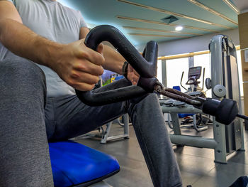 Midsection of man exercising while sitting in gym