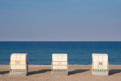 Deck chairs on beach against clear blue sky