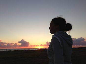 Silhouette man standing on field against sky during sunset