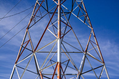 Low angle view of electricity pylon against clear blue sky