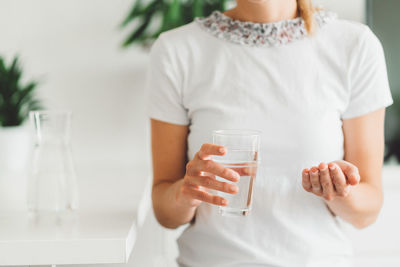 Midsection of woman holding drink at home