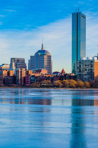 Buildings by river against sky