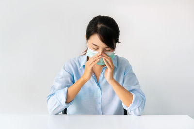 Woman wearing mask sitting against wall