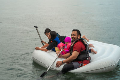 Father with children floating on inflatable ring over lake