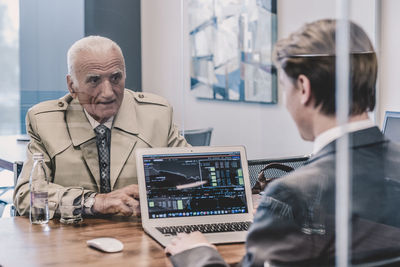 Side view of man using laptop while standing in office