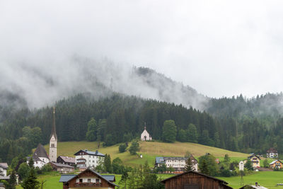 Houses amidst trees and buildings against sky