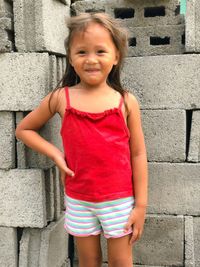 Portrait of cute girl standing against wall