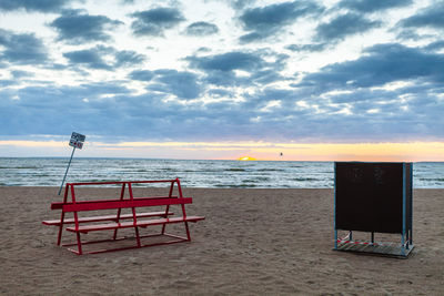 Lifeguard hut on beach against sky during sunset