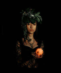 Portrait of beautiful young woman against black background