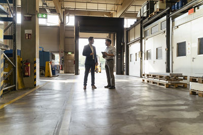 Businessman discussing with colleague while standing at factory