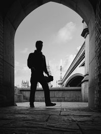 Low angle view of silhouette man walking towards archway against westminster bridge