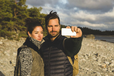 Couple taking selfie at beach during sunset