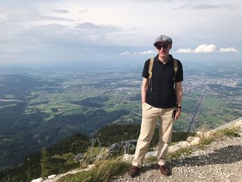 Portrait of young man standing on mountain against sky