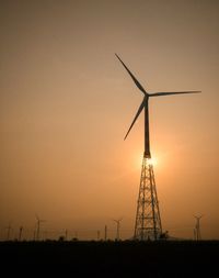 Silhouette windmill on field against sky during sunset