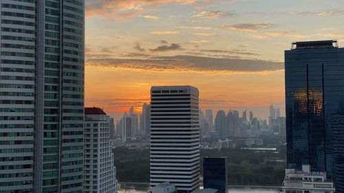 Modern buildings in city against sky during sunset