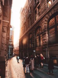 Rear view of people walking on street amidst buildings in city